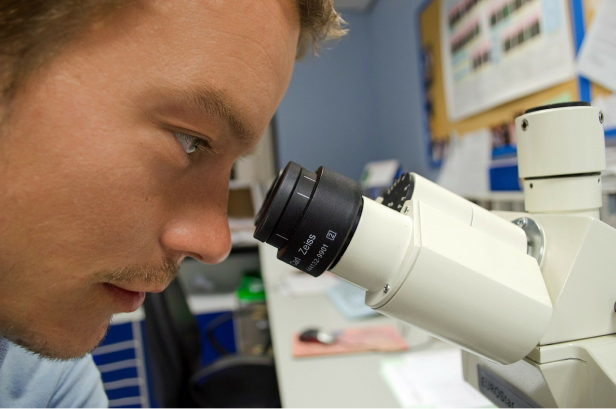 a man looking true a microscope